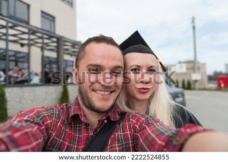 Portrait of Romantic Couple in Love Looking at Camera Making Selfie Woman Confidently Wearing Black Cap and Gown at Graduation