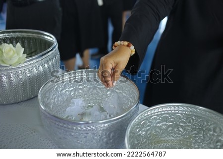 Closeup of man's hand touching the top of the coffin during funeral ceremony.