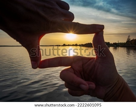 Composition finger frame. Girl hands capture in frame sunset above silent lake.