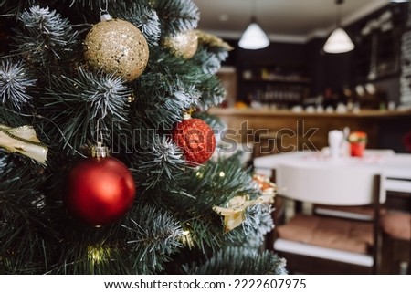 Close-up of Christmas tree with lights garland in modern coffee room with served table, festive decorated empty apartment cafe for New Year celebration, winter holiday concept. Selective focus