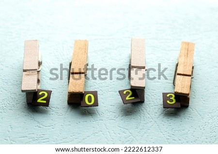 2023 number happy new year small magnetic square withdrawn digits holded by decorative wooden wood white clothespins isolated on blue structured background.new start begging of new year life