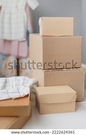 online store of children's clothing, orders and packaging of goods to be sent for delivery. small business and entrepreneurship. children's dresses on a hanger and a cardboard kraft box. eco-friendly