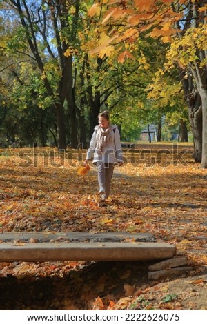 The photo was taken in the Odessa park called Dyukovsky Garden. In the picture, a young woman walks in the autumn park, kicking up leaves lying on the ground with her foot.