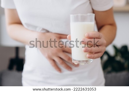 Close up of young caucasian woman with stomach ache and holding glass of milk. Unhealthy female suffers from stale product. Dairy intolerant, Lactose intolerance, allergy, health care concept Royalty-Free Stock Photo #2222631053
