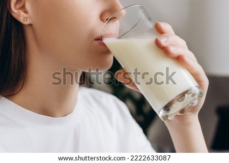 Cropped shot healthy young woman drinking milk with calcium for strong bone at home. Calm brunette girl holding soy milk on glass enjoy with nutrition wellness life. Natural milk fresh concept Royalty-Free Stock Photo #2222633087