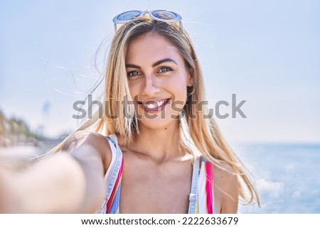 Young blonde girl smiling happy make selfie by the smartphone at the beach.