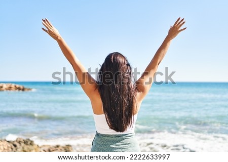 Young hispanic woman on back view with arms raised up at seaside Royalty-Free Stock Photo #2222633997
