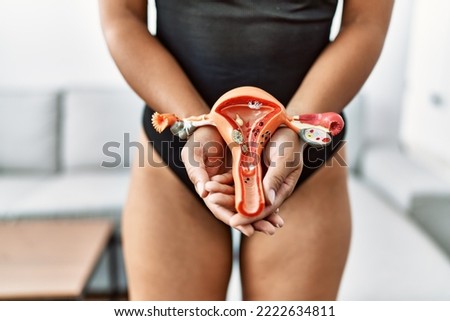 Young african american woman holding anatomical model of fallopian tube at home Royalty-Free Stock Photo #2222634811