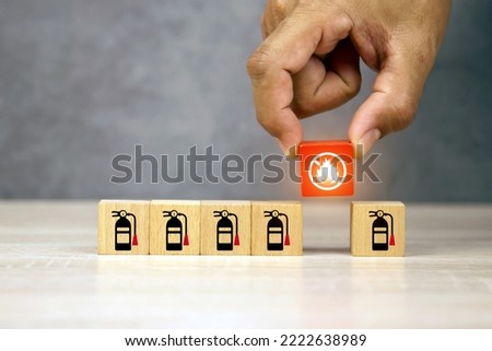Hand choose cube wooden block stack with fire prevent icon with fire extinguisher for emergency protection and safety or rescue concepts in the building.