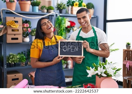 Young hispanic couple working at florist with open sign smiling and laughing hard out loud because funny crazy joke.  Royalty-Free Stock Photo #2222642537