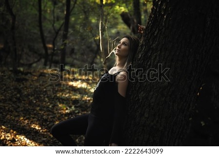 Young blond woman leaning on tree