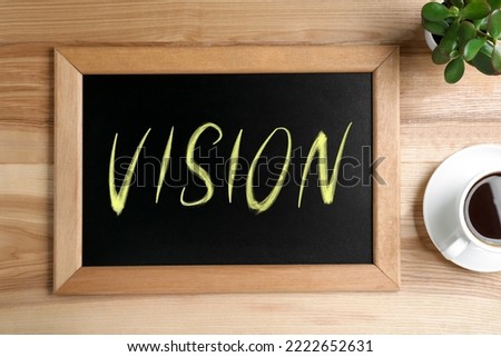 Small chalkboard with word Vision, coffee and plant on wooden table, flat lay