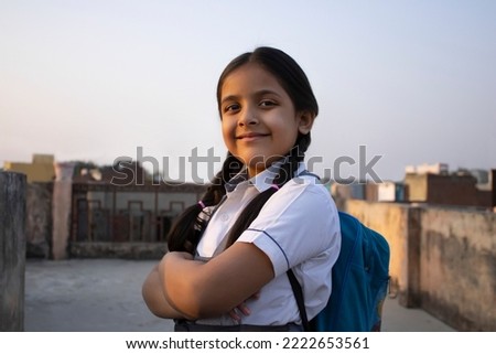 Confident rural Indian school girl standing with backpack Royalty-Free Stock Photo #2222653561