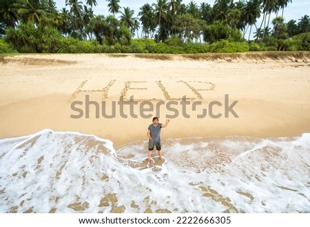 Man stuck on uninhabited island, inscription HELP on sand. Lonely survivor standing in water on deserted tropical beach calls for help. Concept of lost stranded people, castaway, sea island and sos. Royalty-Free Stock Photo #2222666305