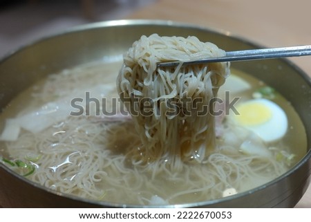 A soup of buckwheat noodles served in a chilled beef and radish broth and topped with sliced Korean pear, cold meats, white radish kimchi, and a ­boiled egg. Originates in Pyeongyang, the North Korea Royalty-Free Stock Photo #2222670053