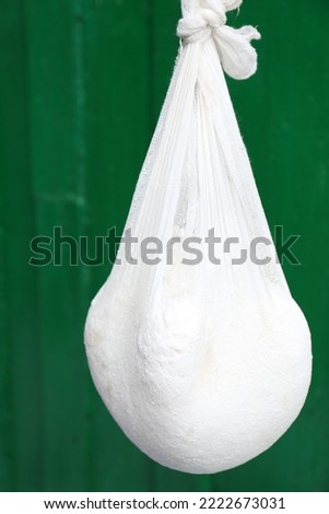 Delicious raw cottage cheese in cheesecloth on green background Royalty-Free Stock Photo #2222673031