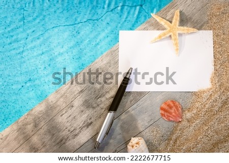 Invitation card without inscription seen from above on a wooden pavement above a pool with a starfish. Atmosphere vacations in summer.