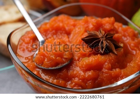 Bowl with delicious pumpkin jam, spoon and star anise on grey table, closeup