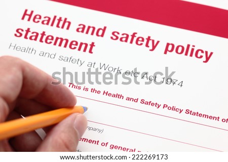 Health and safety policy statement and hand with ballpoint pen.