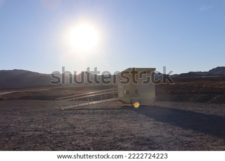 A picture of a single restroom in the middle of the desert