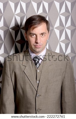 Serious business man standing near the wall - stock photo