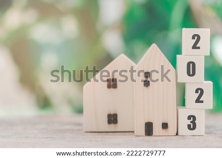 Wooden house model with wooden block number 2023 and copy space using as background concept to save money buying house, new year property, business, real estate and property concept.
