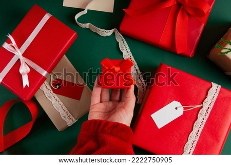 Directly above woman's hand holding a ring box with presents for valentine's day