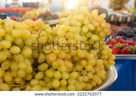 Yellow white ripe grapes in bunches with leaves lie on the counter of the market