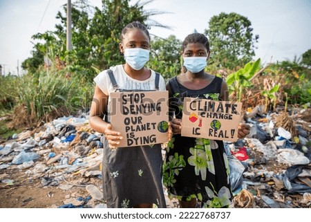 Young african girls holding signs written: stop denying our planet is dying.