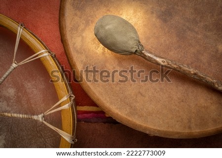 two handmade, native American style, shaman frame drums covered by goat skin with a beater Royalty-Free Stock Photo #2222773009