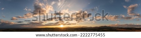 Dramatic clouds and sun in the sky at sunset over the mountain Royalty-Free Stock Photo #2222775455