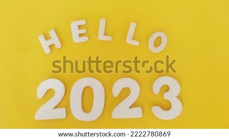 wooden letters on a yellow background, inscription hello 2023.