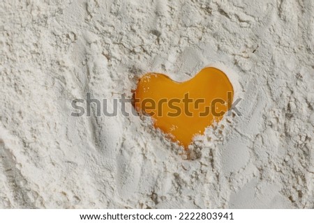 Egg heart on flour. I love to bake! Close-up of yolk on flour in the shape of a heart, full frame