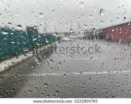 Rain drops on the car window, empty parking and urban city landscape through the rain. Autumn background with rainy glass