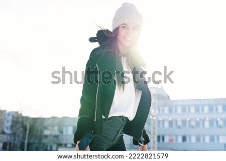 Beautiful woman at stylish jacket having fun, laugh on outdoor ice skating rink. Cheerful pretty young woman skate on Christmas ice rink. Winter holiday outside activity