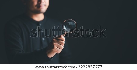 man use magnifying glass on black studio background. male use hand lens glass magnifier search for best option, sale deal, Data Search, Searching for information, Human Resource Management HRM concept