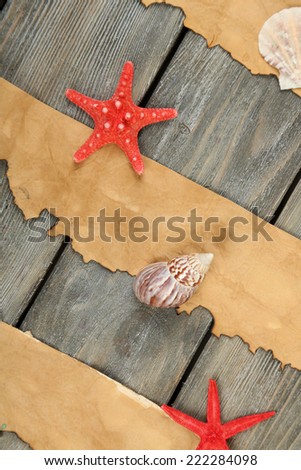 Decor of seashells, starfish and old paper on wooden table background