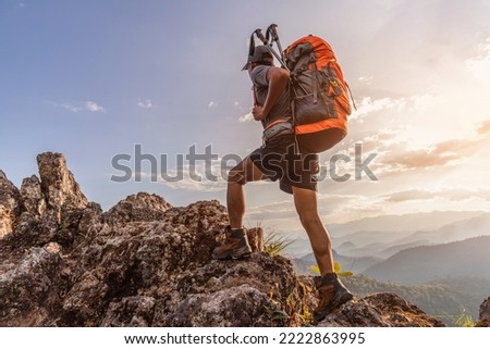 Male hiker with backpack walking on top rock mountain landscape and beautiful view sunset background.Hiker men's hiking living healthy active lifestyle. Royalty-Free Stock Photo #2222863995