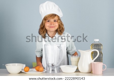 Cooking children. Chef kid boy making fresh vegetables for healthy eat. Portrait of little child in form of cook isolated on grey background. Kid chef. Cooking process.