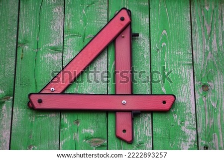 Red number four sign from car reflector triangle on green wooden wall as the house number. 