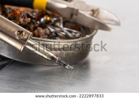 Soldering iron with tin, rosin and pliers on workshop table Royalty-Free Stock Photo #2222897833