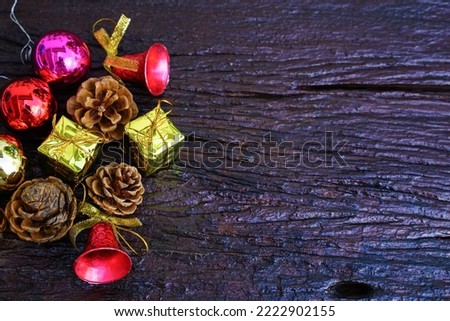 New Year and Christmas gift themed decorations on wooden background, consisting of a golden gift box.  shiny colored balls  Dried pine cones and small bells  free space for design
