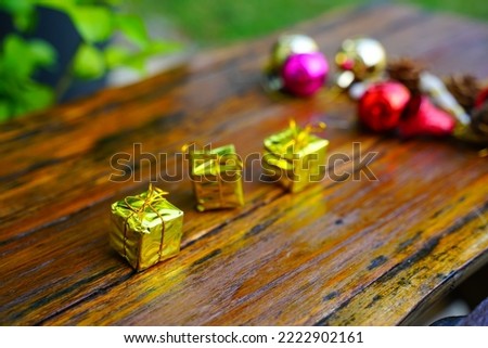 New Year and Christmas gift themed decorations on wooden background, consisting of a golden gift box.  shiny colored balls  Dried pine cones and small bells  free space for design