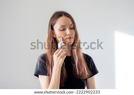 Young woman gets facial cleansing with an ultrasonic scrubber to exfoliate her face and remove acne.