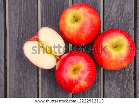 Apple Pink Lady, cut in half, placed on a wooden floor, wooden table