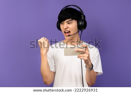 Young Asian man standing on violet background Using a mobile phone.