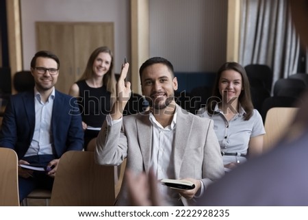 Businessman take part in educational, motivational training event seated with colleagues attend together in seminar, raises his arm for ask question, participate in voting, having opinion to share it Royalty-Free Stock Photo #2222928235