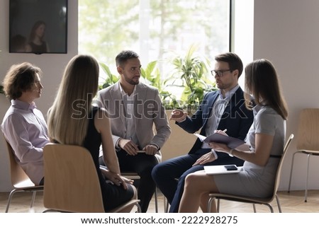Five teammates, staff members communicate during corporate briefing in modern office, employees listen to team leader express opinion, work together on collaborative project. Teamwork, workshop event Royalty-Free Stock Photo #2222928275