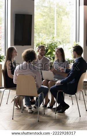 Staff meet in briefing for share ideas, working on project, vertical shot. Five positive smiling employees take part in seminar or teamwork communicate seated in circle looks satisfied by cooperation Royalty-Free Stock Photo #2222928317