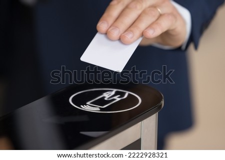 Close up shot unrecognizable authorized person, businessman in formal suit swipe pass card to electronic card reader passing security system checkpoint in modern office area before working day start